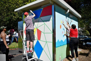 People painting a toilet block with bright colours