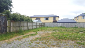 A vacant piece of land with sparse grass and gravel