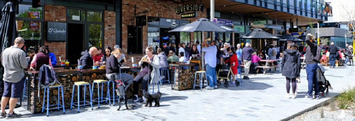 People sitting in the sun outside the Riverside Market
